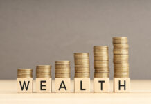 Creating and Preserving Your Legacy with a Dynasty Trust Wealth word in wooden blocks with coins stacked in increasing stacks. Wealth increasing concept. Copy space