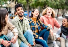 MILLENNIALS THE TIME TO PLAN IS NOW Millenial friends sitting together at city place on life style concept - Happy guys and girls having fun talking around Barceloneta streets - University students on travel vacation - Bright filter