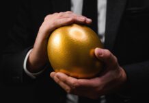 Helping Clients Pass On Their Wealth, Is Outright Distribution The Right Choice? Golden egg in hands of elegant businessman as symbol of guaranteed success, profit or wealth., selective focus